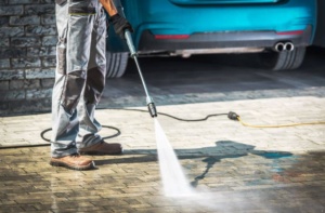 Man cleaning driveway using power washer.